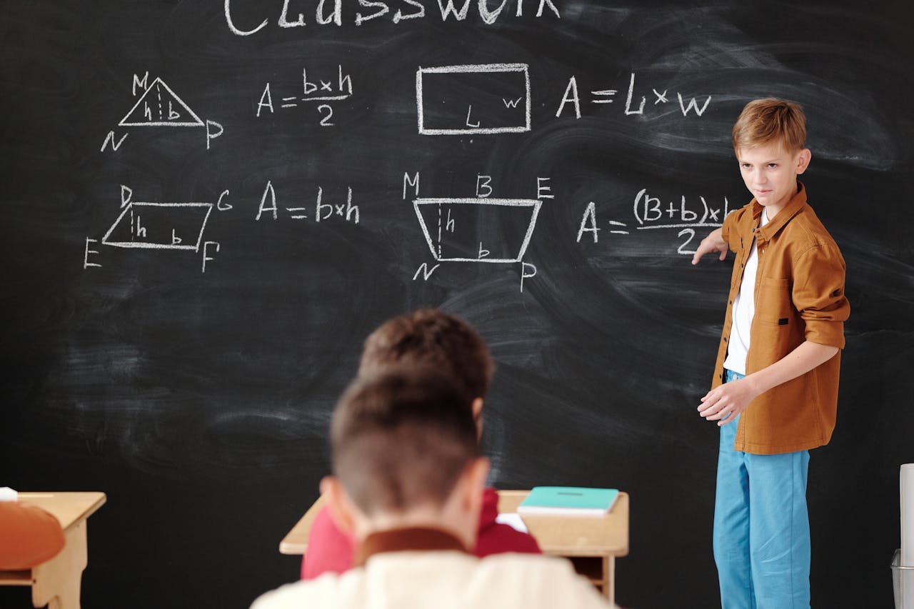 why-choose-us A young student explains math formulas on a blackboard during classwork.