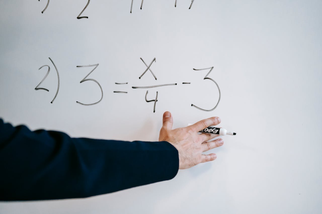 services-03 A hand writing a mathematical equation on a whiteboard with a marker.