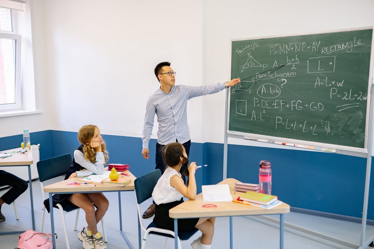 about-01 Teacher pointing at chalkboard with students in classroom learning geometry.